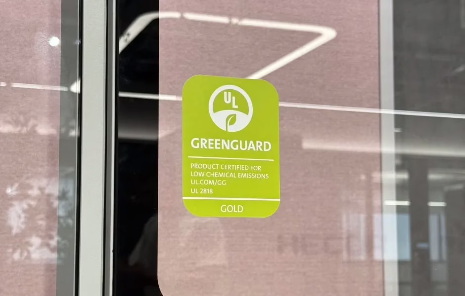 UL GREENGUARD Gold certification sticker on a soundproof pod glass door, certifying the product for low chemical emissions and high indoor air quality standards.